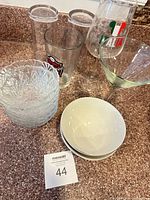 Full lot showing stacked cut-glass bowls, ceramic bowls, tumblers, pint glass, wine glass, martini glass