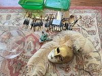 Lot overview: glass punch bowl with ladle, Venetian mask with feathers, mixed flatware, green plastic containers, frog figurine