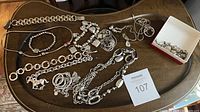 Overview of all necklaces, bracelets, charm chain and box of loose charms laid on table