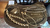 Overall view of all gold-tone necklaces, bracelets, earrings on tray