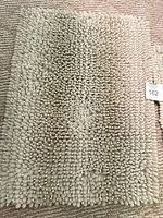 Full view of first beige-cream chenille bath rug