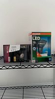 Front view of boxed Sylvania LED bulb and boxed landscape spotlight fixture