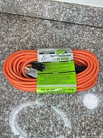 Coiled orange extension cord with factory label showing brand and specs