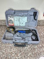 Full set inside carry case showing saw, spare blade pack, manual, dust adapter and power cord