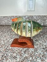 Full side view of segmented wooden fish on stand