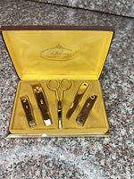 Open case showing five gold-plated tools in yellow satin interior