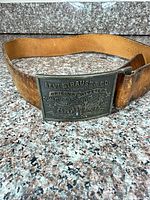 Full view of belt coiled with buckle facing front showing Levi Strauss & Co. branding