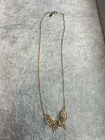 Full view of gold plated butterfly pendant necklace laid out to show chain length and overall design