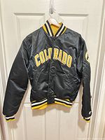 Front view of black Colorado Buffaloes varsity jacket showing COLORADO appliqué and overall style