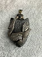 Front view showing eagle, feather, onyx cabochon, green stone, bail and overall form