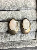 Front view of both earrings showing oval mother of pearl and patinated sterling frames