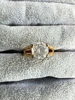 Front view of gold-tone solitaire ring with round clear stone