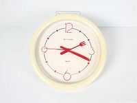 Front view of cream clock with red cutlery hands and numerals