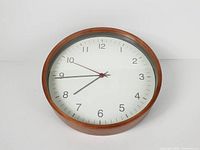 Front view showing wood frame, white dial, numerals, hands