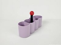 Front angled view showing four lavender cylinders, black post, red knob