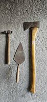 Axe, hammer and trowel hanging on wall