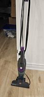 Full view of Bissell gray and purple corded stick vacuum standing upright