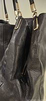 Close view of side, pebbled leather texture, gold-tone hardware, exterior slip pocket with zipper
