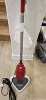 Full view of red Dirt Devil steam mop with handle, base and attached power cord