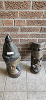 Two carved wooden tribal sculptures standing on tile floor against brick wall