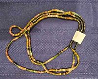 Full view of necklace showing multicolor gemstone strands and attached tag