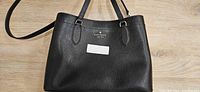 Front of black Kate Spade leather tote, showing overall design and logo