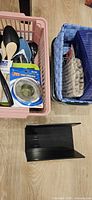 Overall view of pink basket with utensils, blue woven basket, grey bin, black file holders