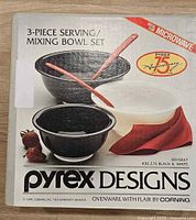 Front of sealed Pyrex Designs box showing 3-piece black & white bowl set and anniversary logo
