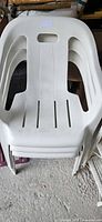 Stacked white plastic chairs showing overall design and condition