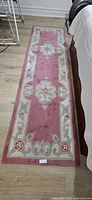 Full view of pink floral rug runner beside bed