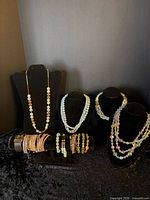 Group view showing four necklaces on busts and ten bracelets in front
