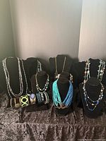Group view of necklaces on stands with bracelets arranged at base