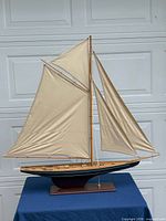 Front view of wooden sailboat model showing sails, hull, stand