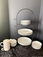 Full set displayed on stand showing plates in various sizes and teapot