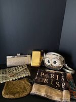 Group shot of five gold handbags and two scarves