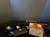 Group shot showing six wallets, black and tan items with straps visible