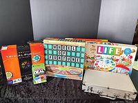 All six items grouped: four boxed board games, one card game, poker chip case