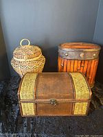 Three trunks grouped: rectangular chest, round wicker basket, cylindrical slat trunk