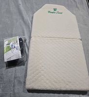 Folded Nikken Kenko Seat cushion with arm sling package beside it