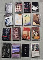 All 16 cassette tapes laid out in 4 x 4 grid showing fronts of cases and loose cassette