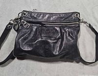 Front view showing overall style, hardware, long strap, front zip pocket