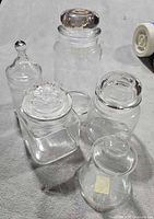 All five clear glass apothecary jars with lids displayed