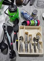 Overview of flatware in tray, cooking utensils, jug, mug, insulator