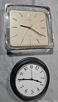 Front view of both wall clocks showing designs and faces