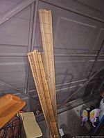 Three rolled bamboo blinds leaning against garage door