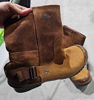 side view showing suede shaft, leather foot, Sorel logo, buckle strap