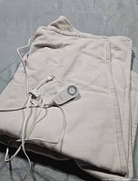 Folded beige microfleece heated throw blanket with attached white cord and grey controller shown on surface