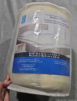 Rolled sealed memory foam topper with label showing size and brand