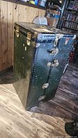 Front view showing dark green exterior, brass latches and lock hardware