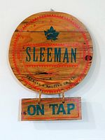 Front view of round Sleeman wood sign with hanging On Tap plaque